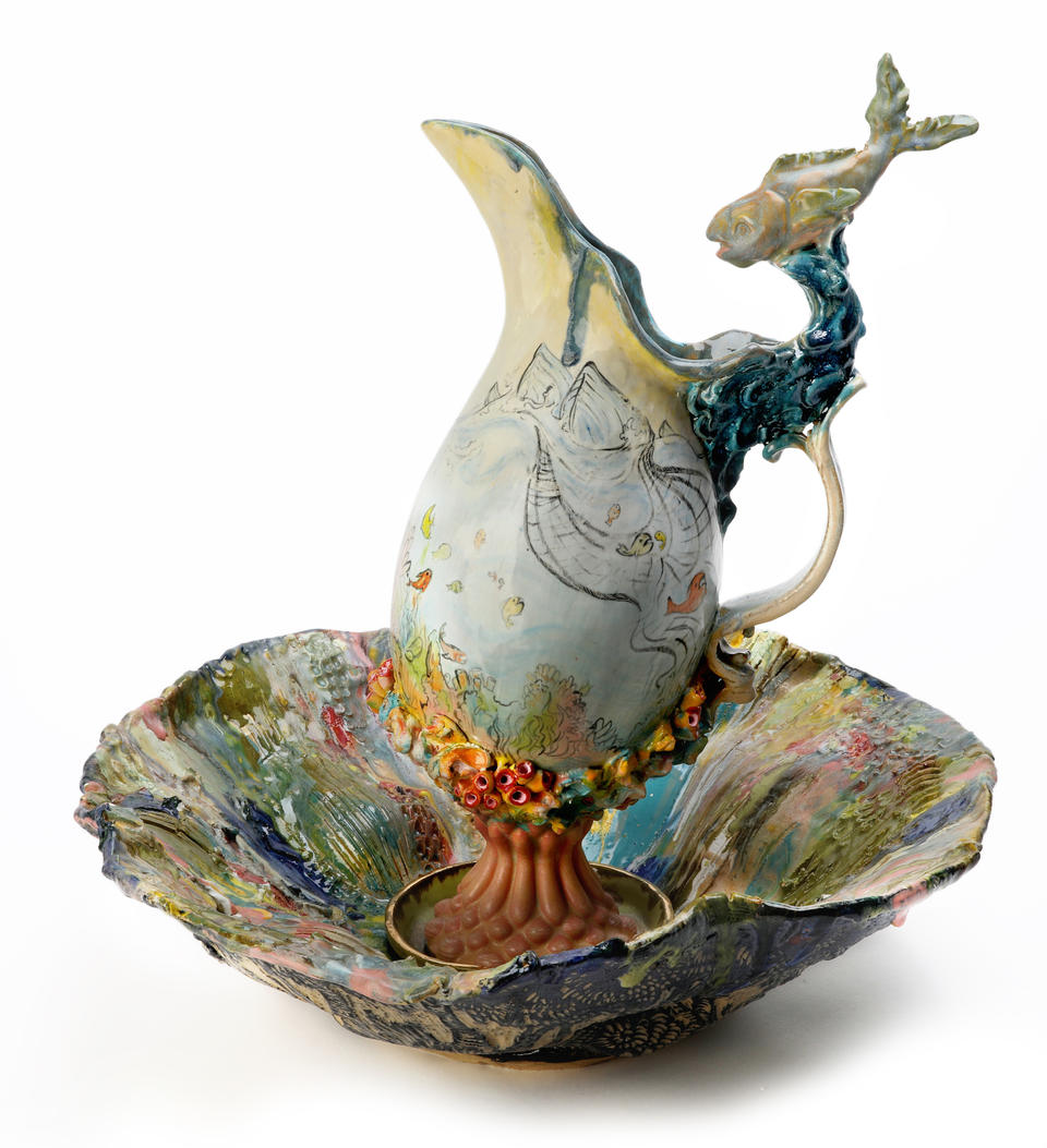Pitcher and Basin set featuring a pitcher illustrated with fishing boats and a sculpted fish and a colorful basin interior with trees on the outside. 
