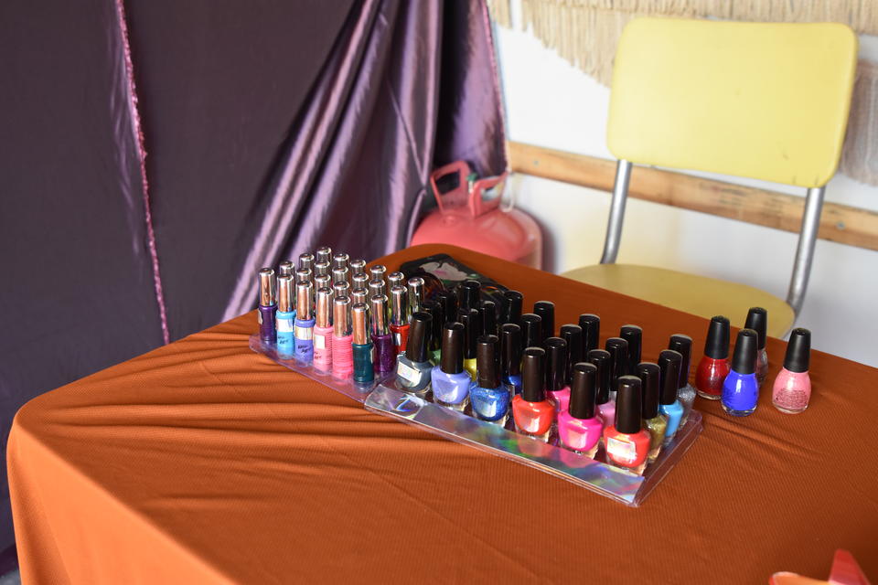 Close-up of a table and chair inside a U-haul with neatly organized nail polish in bright colors