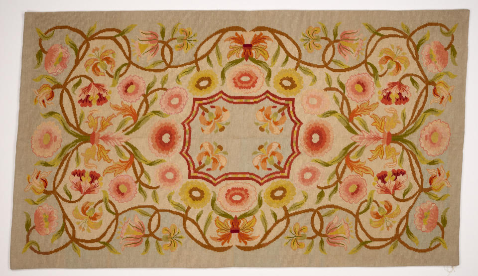 Floral design with scalloped rectangular center medallion. Vines with salmon-colored flowers twist around it. Palette includes tan, peach tones, green, and light blue.
