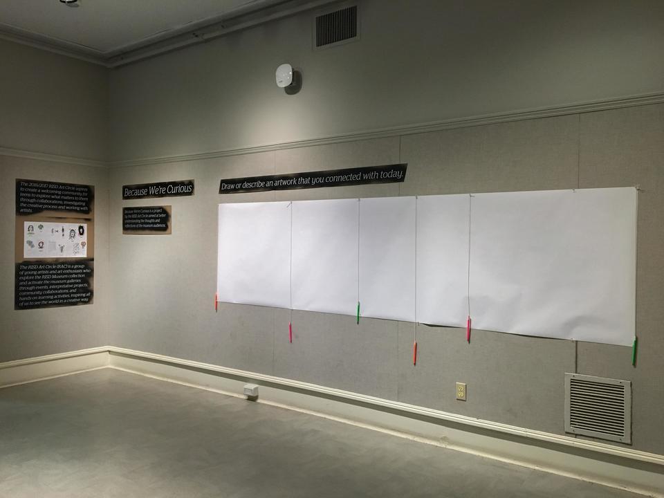 Wall with cardboard signs with laser cut lettering, and a large sheet of blank paper with pens attached.