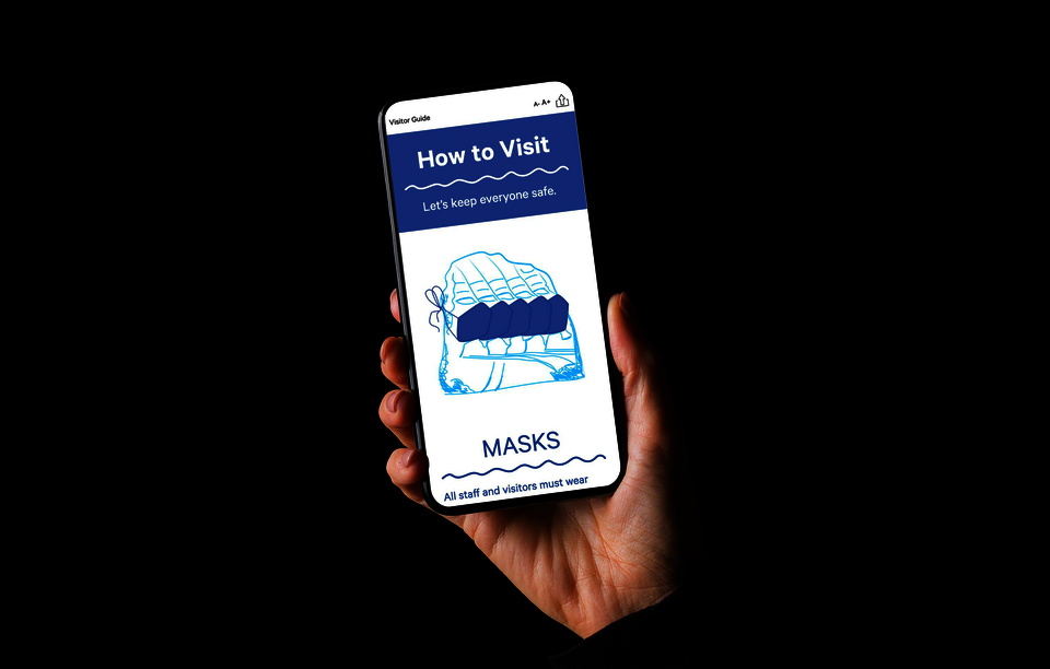 A light-skinned hand holds a cell phone. The phone’s screen says, in white and blue text: How to Visit: Let’s keep everyone safe. Masks: All staff and visitors must wear.”