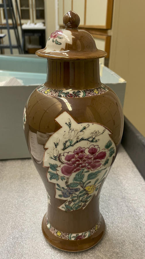A brown and white porcelain covered vase with pink, green, blue, and yellow floral decorations. 