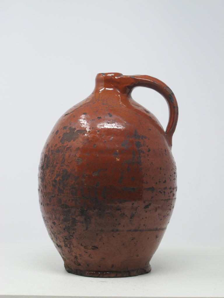 A bulbous orange ceramic jug with a handle. 