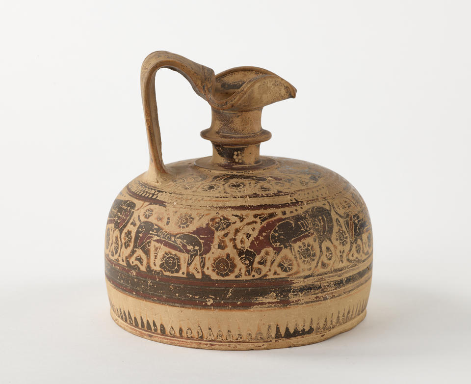 A terracotta wine jug with a thick handle, wide cylindrical base, smaller neck, a folded rim and brown and black decorations that are worn and depict abstract shapes and animals. 