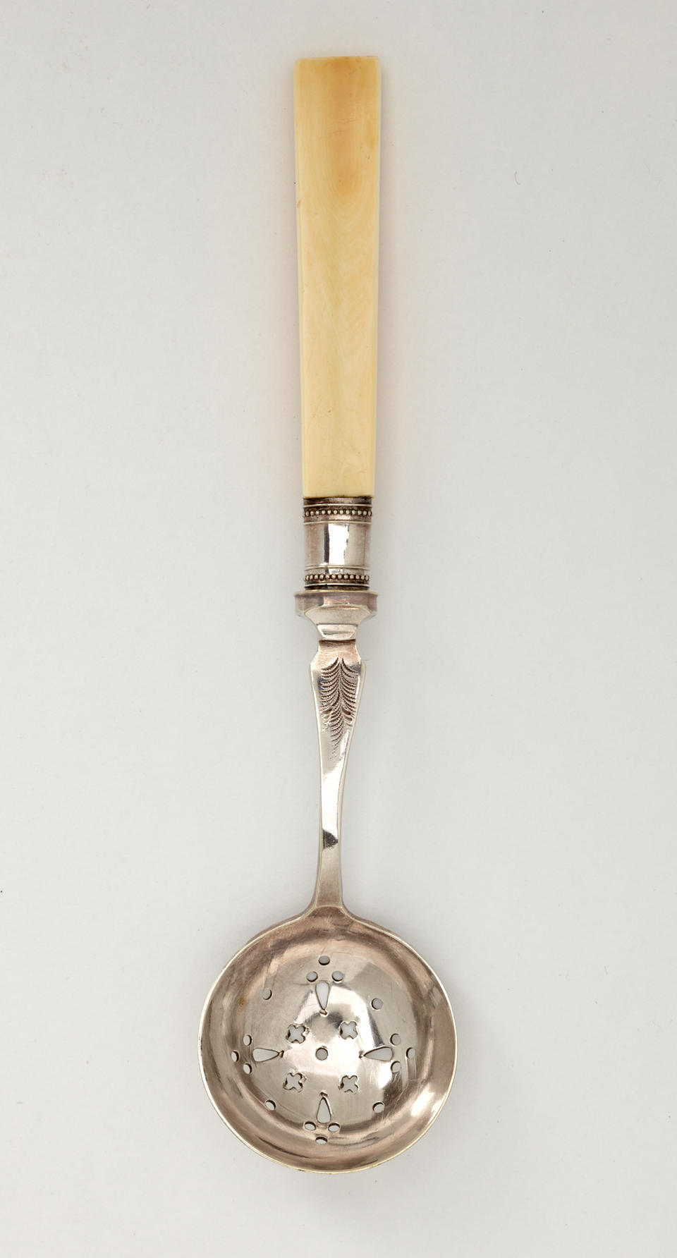 A silver sugar sifter with small cutouts in the bowl, the end of the handle is ivory. 