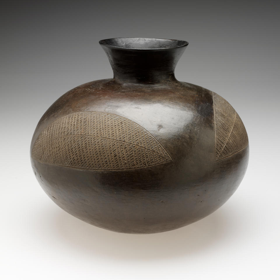 A bulbous vessel with a rounded, flared neck. Two large, abstract leaf-shaped designs are scratched into the shiny surface. 