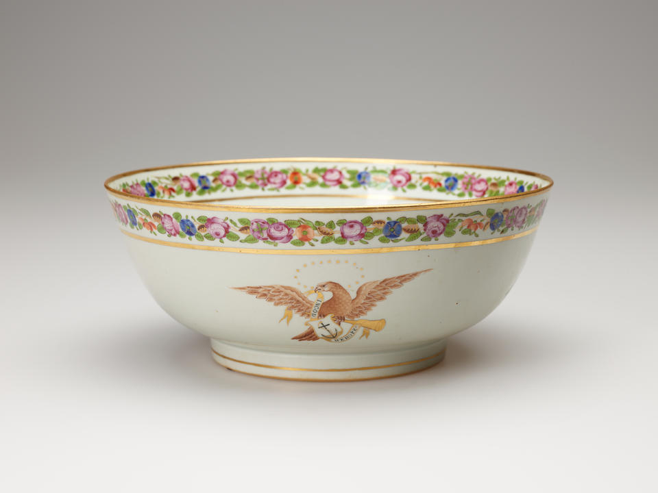 A white bowl with a flowered rim. Image of an eagle with an anchor in the center. 