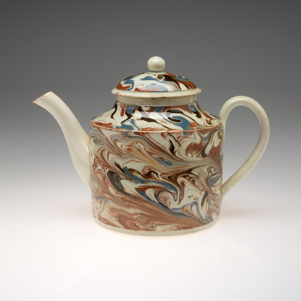 Teapot with a swirling, marbled design on the body and lid in brown, blue, black, and cream. Spout, handle, and rounded finial are solid cream colored. 