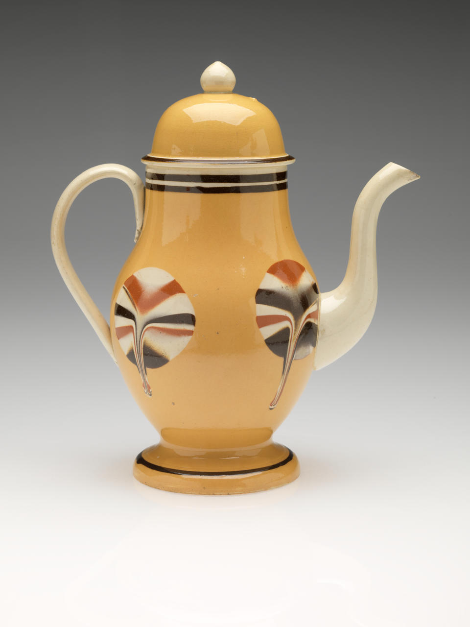 A teapot with a foot, spout, handle, and lid with a finial. The glaze is cream, orange, and brown, the body of the vessel has dripping symmetrically stripped glaze.