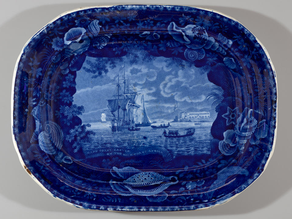 A transfer-printed earthenware platter with dark blue decorations depicting a coastal scene.