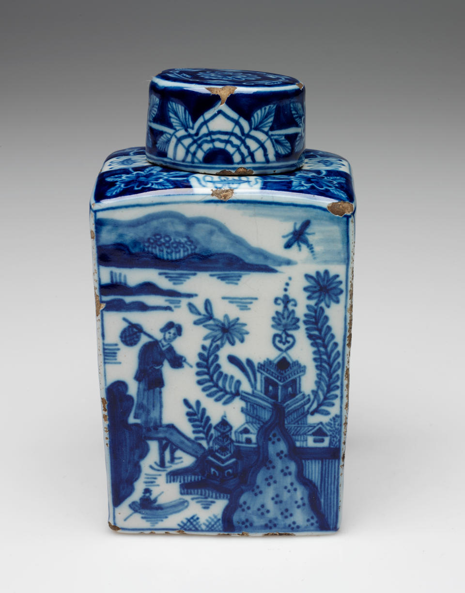 A rectangular vessel with blue and white architectural, landscape, and floral decorations. The lid is circular and has floral decorations as well. 