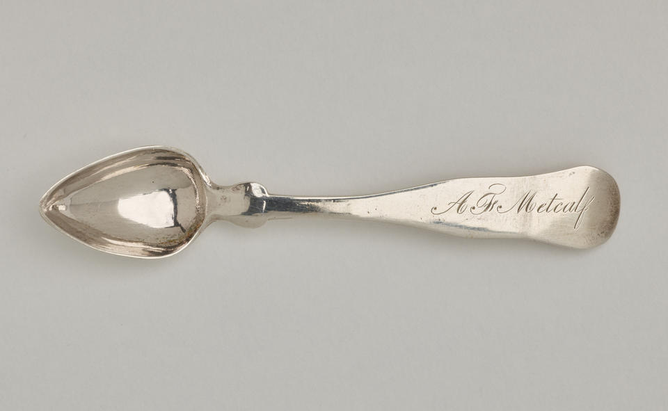  A silver salt spoon the bowl comes to a pointed tip, the neck is thin, and the handle is thicker and rounded at the end. 