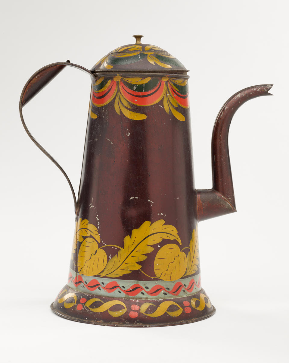 A tin-plated iron, black asphaltum, polychrom coffee pot. The decorations are yellow, white, and orange and abstract, floral, and swirled. The spout has a right angle and then a curve. 