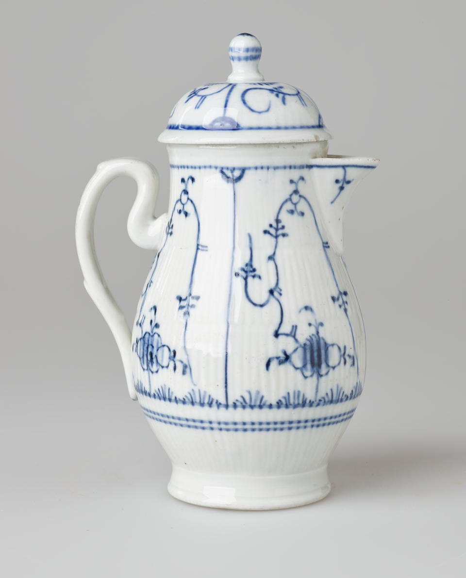 A white ceramic chocolate pot with delicate blue decorations with ribbed body, spout, handle, and foot.