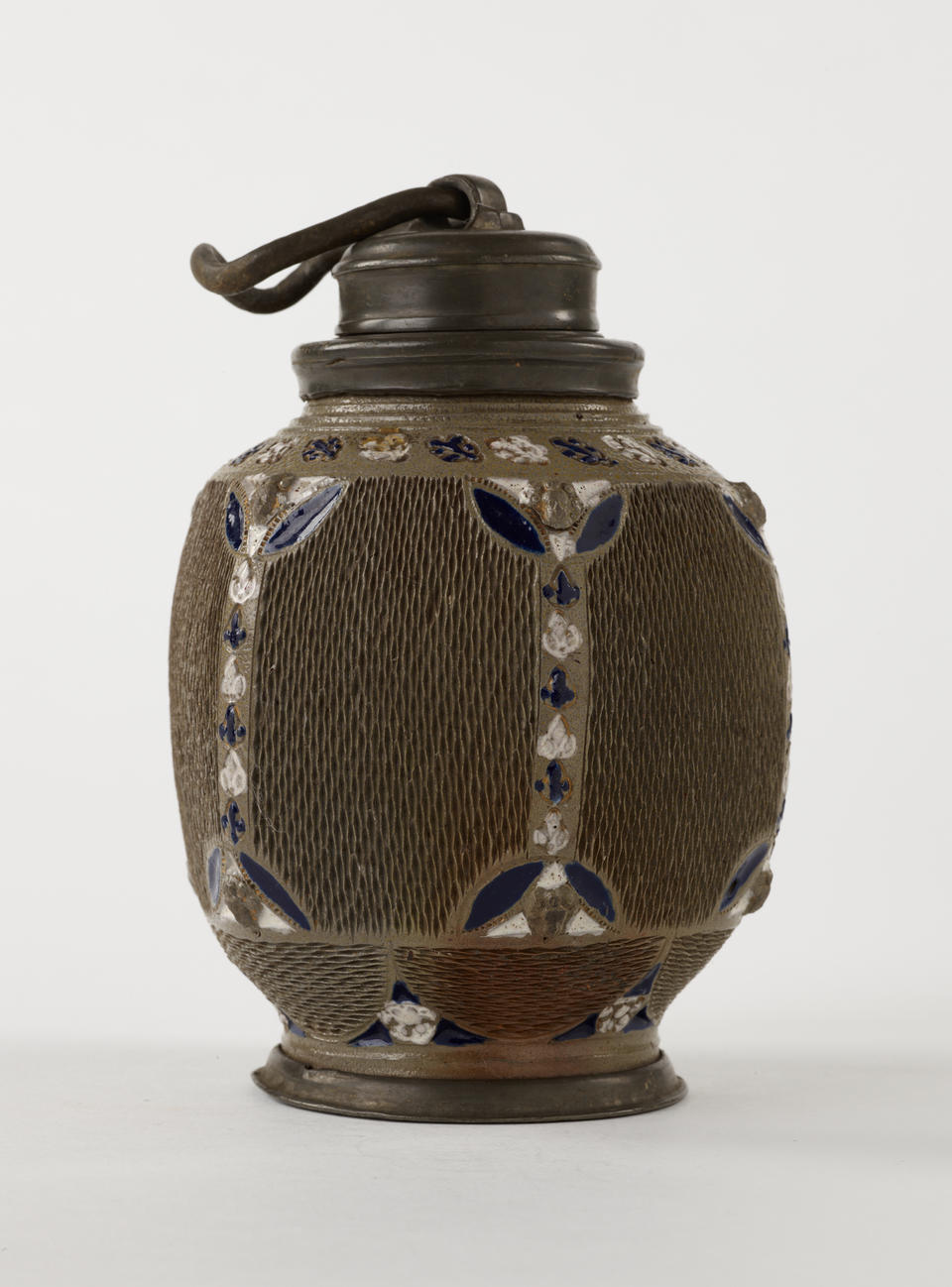 A ceramic and salt glaze flask that is dark gray, blue, and white. The body is angular and has textured sections whereas the foot and top are rounded. 