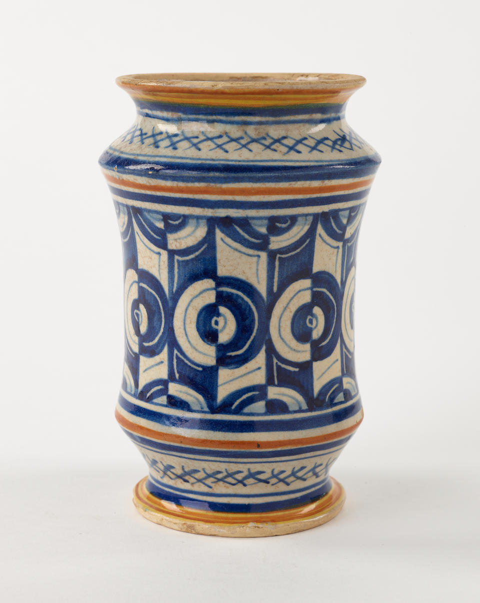 A tin-glazed earthenware jar that has white, orange, and blue symmetrical decorations.