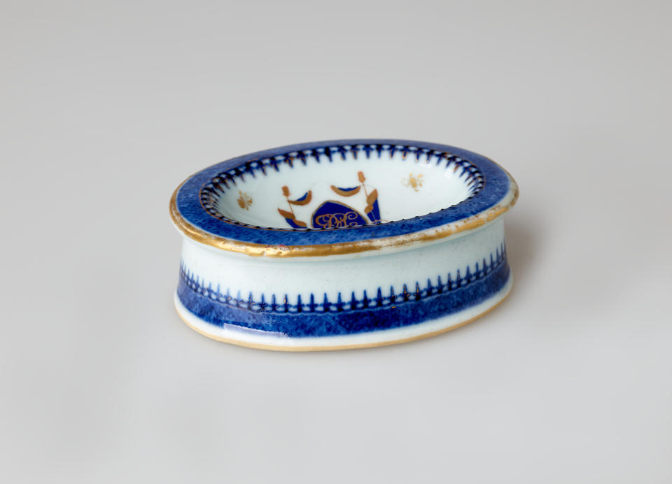 An oval porcelain white salt container with blue and gilded decorations. 