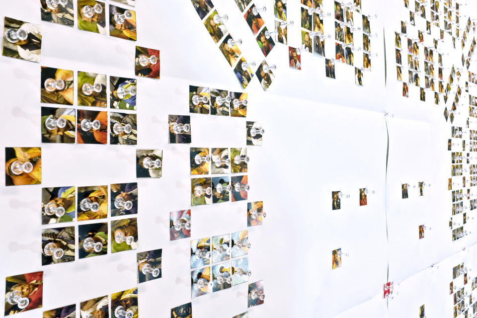 This image shows an installation of numerous paper cutouts pinned on the wall.