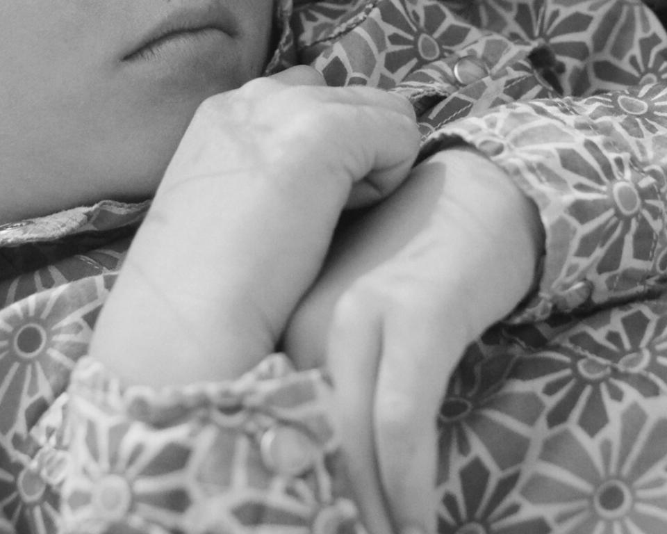 the hands of a young girl resting on her chest, her floral shirt 