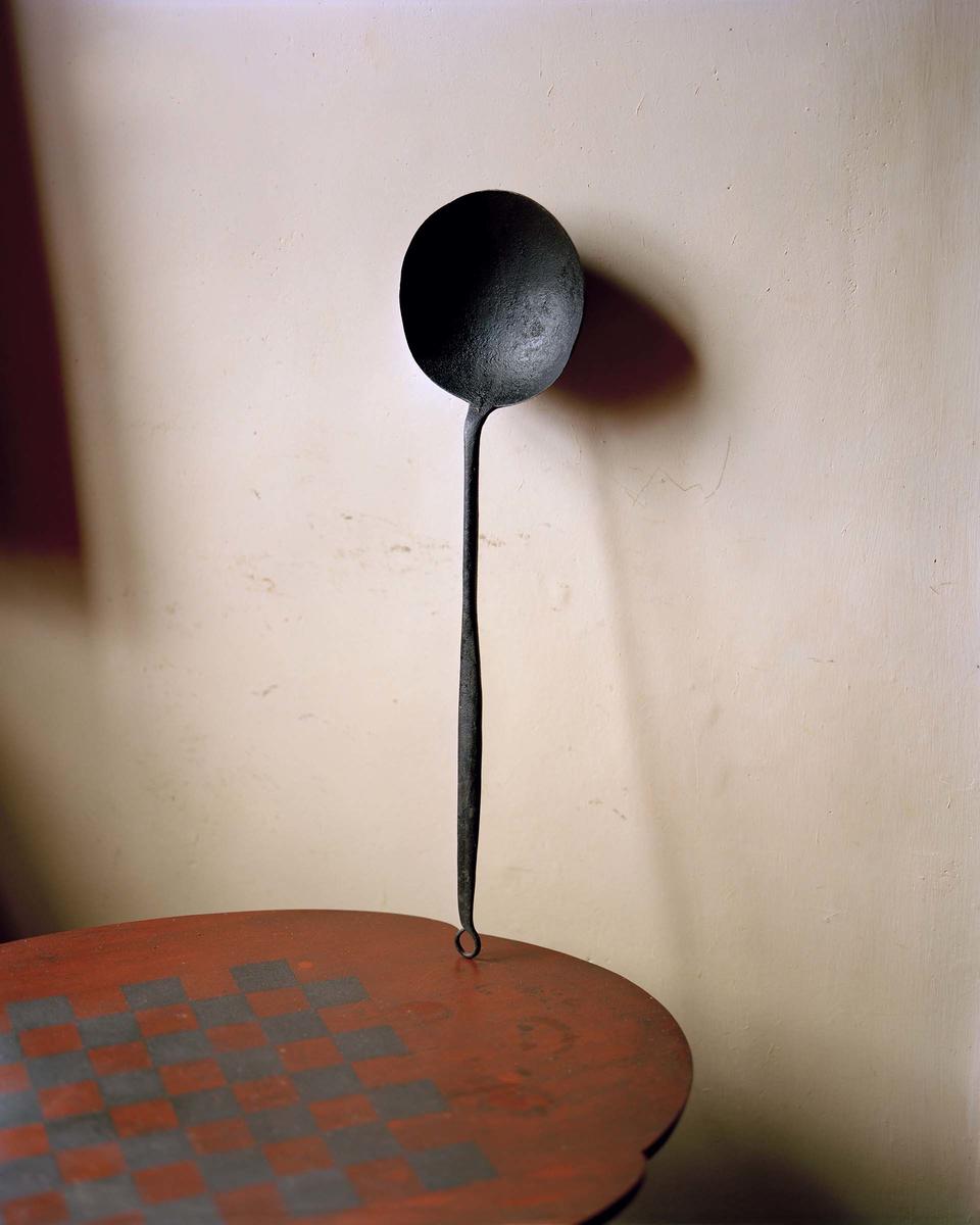Cast iron cooking spoon standing on top of a small table.