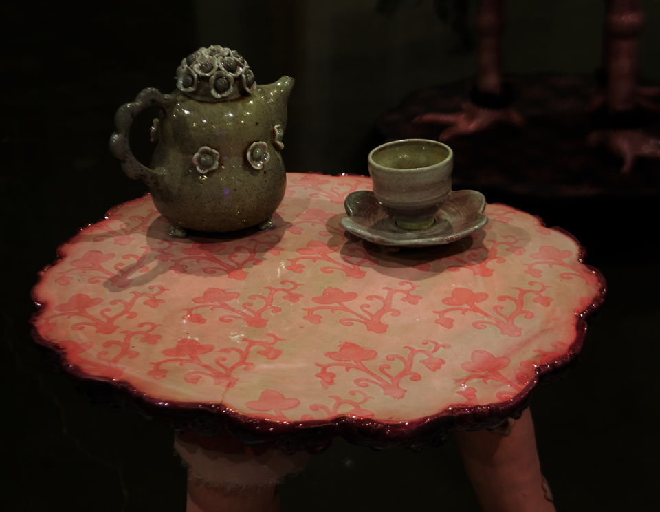 Grey-green teapot, saucer, and cup adorned with ceramic flowers.