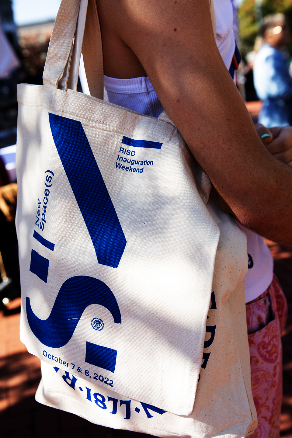 Close-up of a young white woman holding a canvas tote with the letters N and S in blue