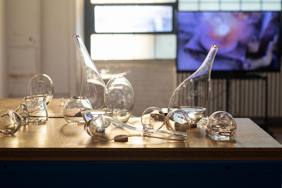 Examples of blown glass vessels sit on a wooden table top.