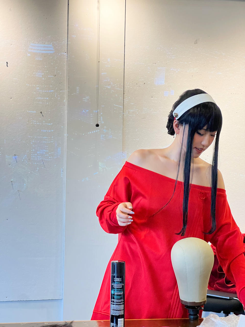 The author dressed as Yor Forger, a female character from the Japanese anime and manga series Spy × Family, doing a demo on wig styling in class.