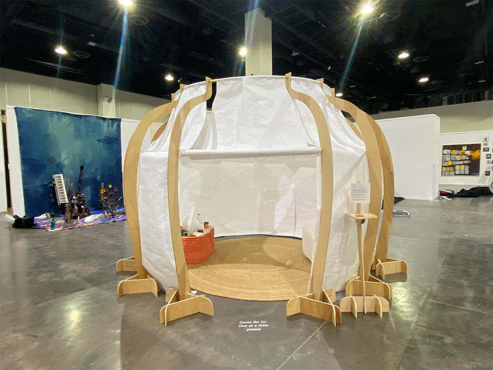 A large temporary wood and tyvek structure stands in a large convention center