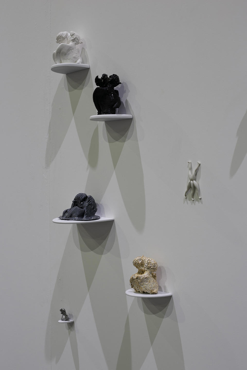 A grouping of sculptures of various materials sitting on individual shelves