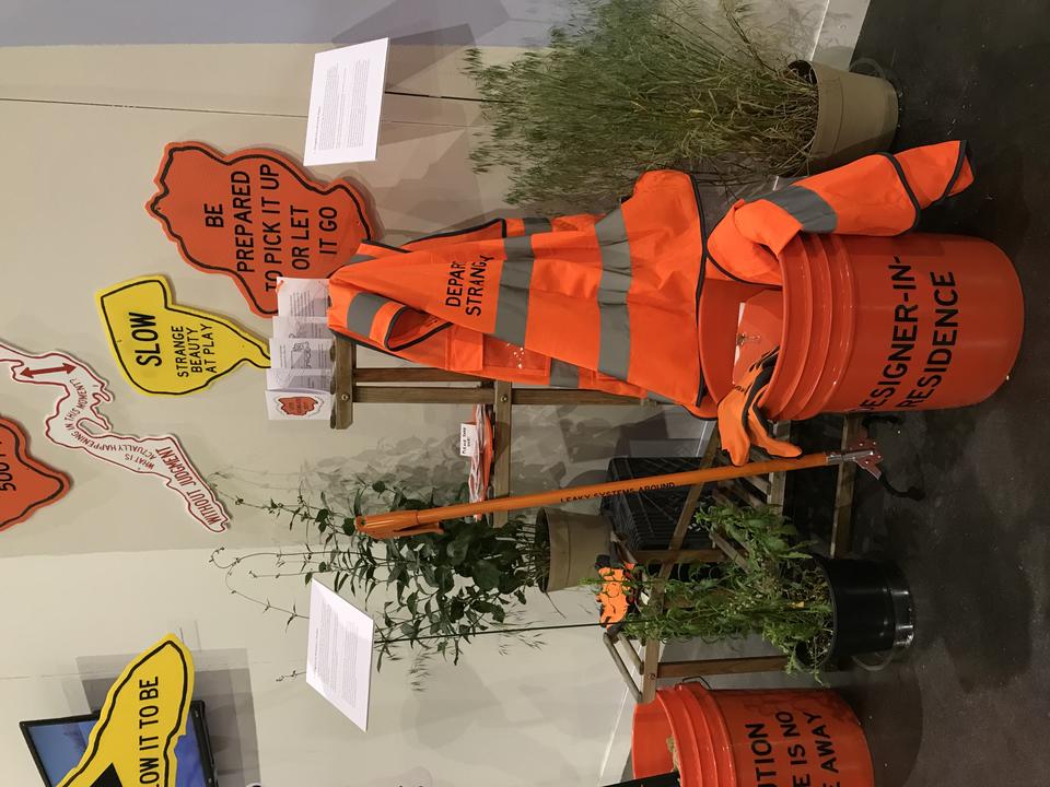 Installation view of a Designer-in-Residence Toolkit, including bucket, trash grabber, vest, pamphlet, clipboard, stickers, and gloves