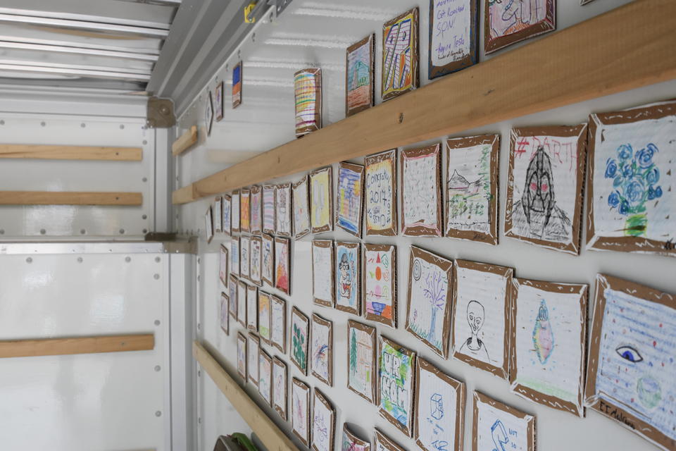 Inside of U-haul Truck covred with small pieces of cardboard that have drawings on them. 