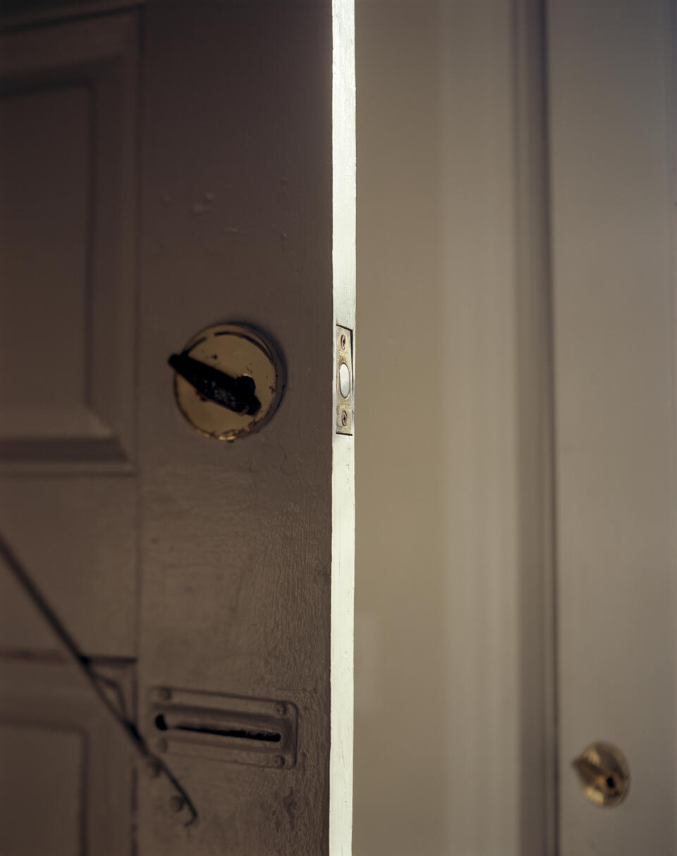 Photograph of two white doors. The open door on the left's lock latch is angled left. In the bottom right is the the second door's lock. it is also angled left.