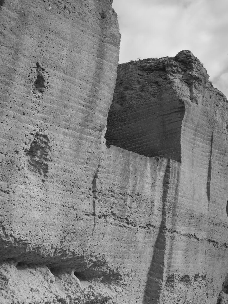 Black and white photograph of a quarry in Spain, with holes that seem erosion, but that are made because of bullets. The police used the space as a practice shooting field