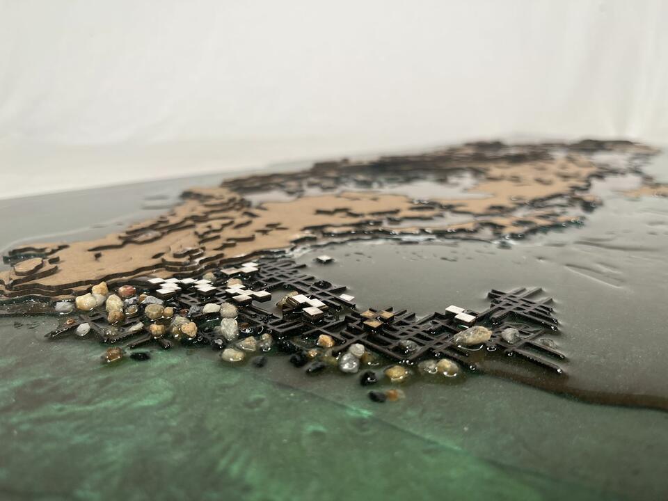 A model made of clipboard and resin showing the physical relationship between original island and future construction.
