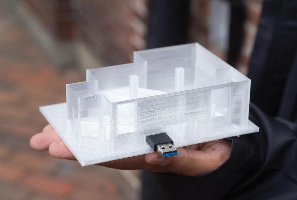 A 3D-printed model of a room with a USB stick mounted on the side of it.