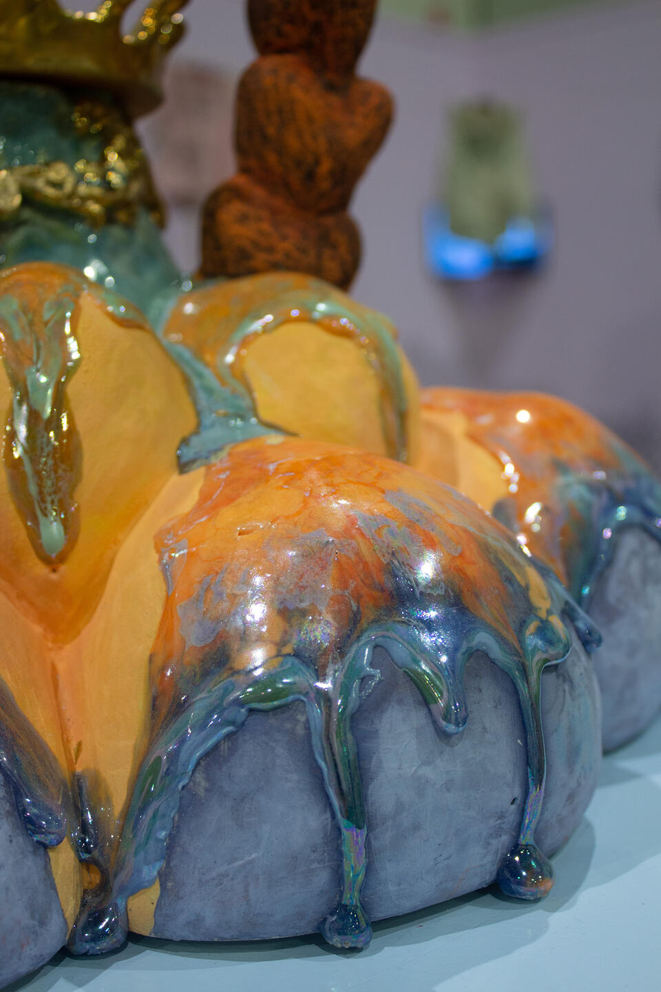 Close-up of a glossy ceramic flower sculpture with vibrant hues, featuring drip-like textures. 
