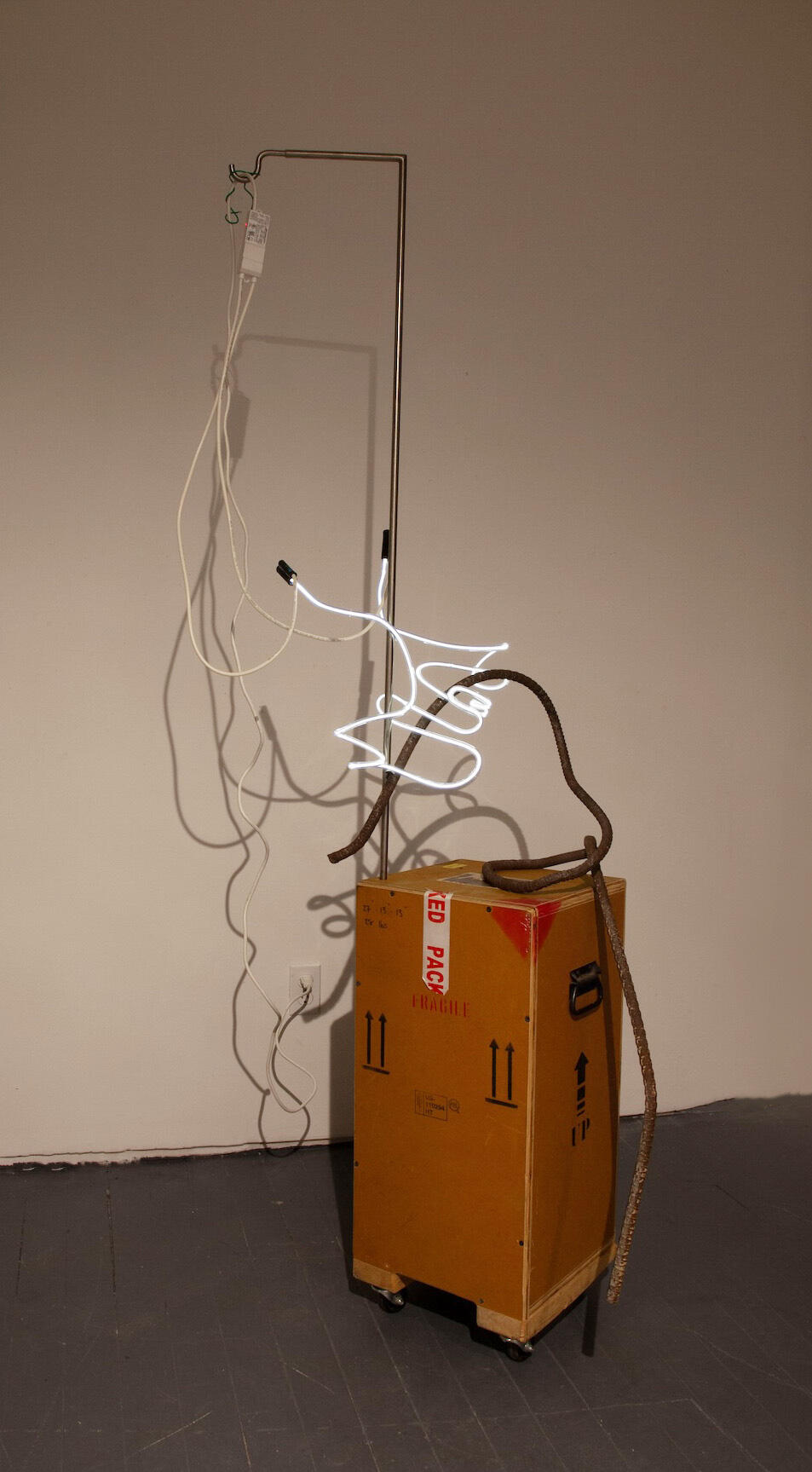 an art crate on wheels with a white light squiggle, a mangled piece of rebar, wiring, and a stainless steel hook 