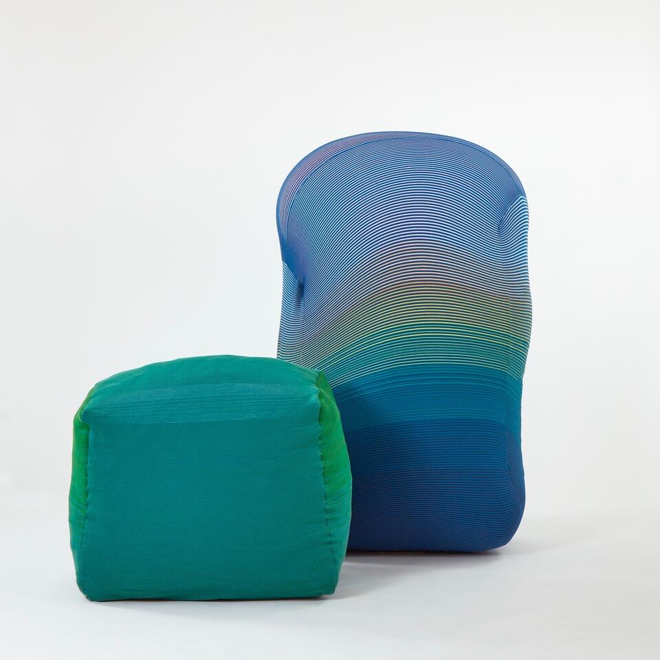A cushioned bench covered in green wool knit sits on the left side. A blue inflated Knit Wiggle wall sits next to it.