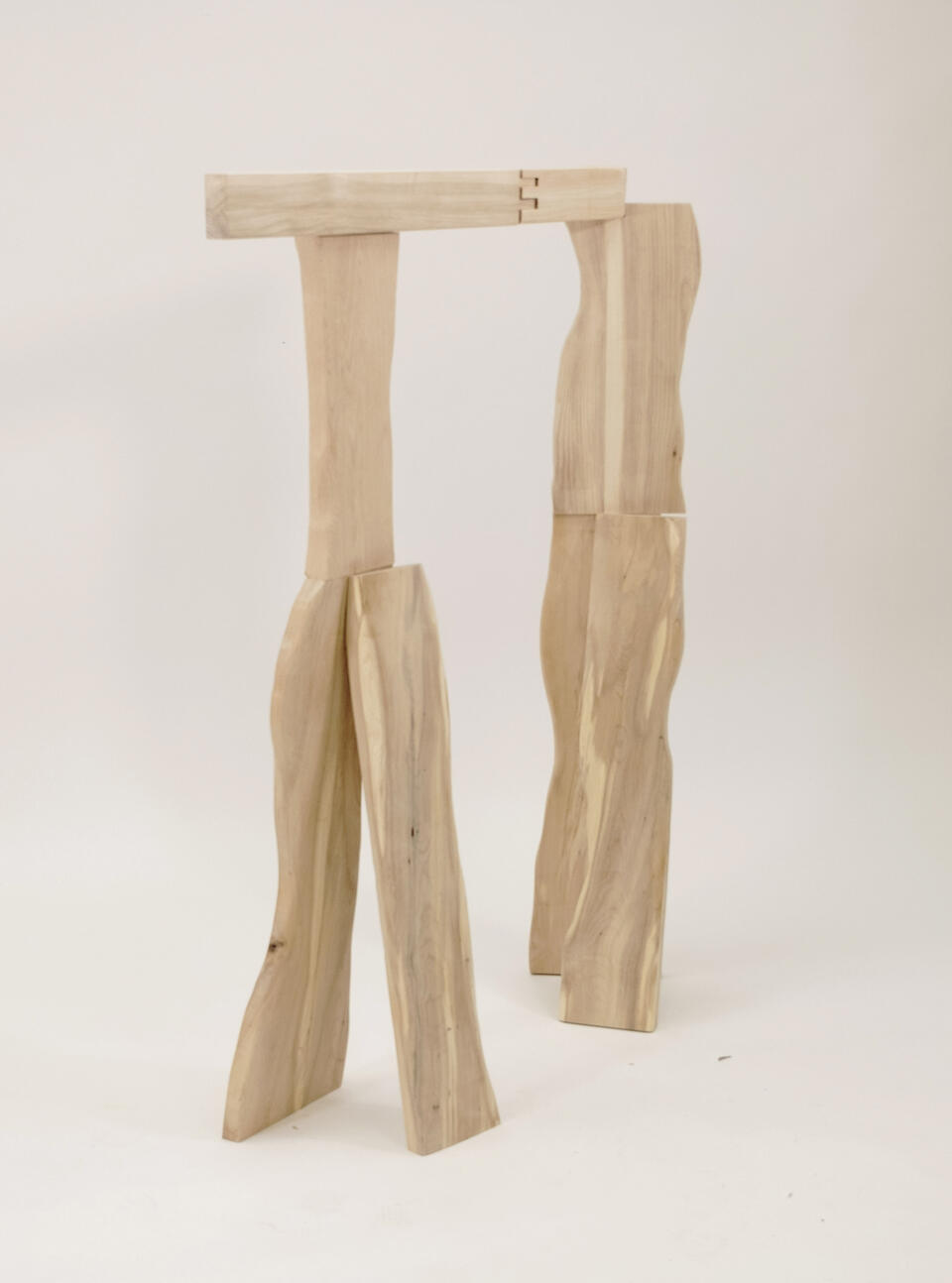 A wooden coat rack inspired by the standing posture of a person in a living room, made from three different types of wood.