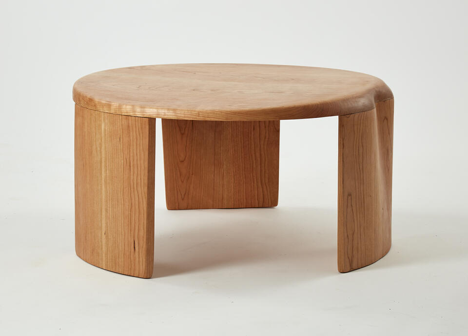 This is a coffee table consisting of three legs and a tabletop. Both the tabletop and the legs are joined together with a slight curvature.