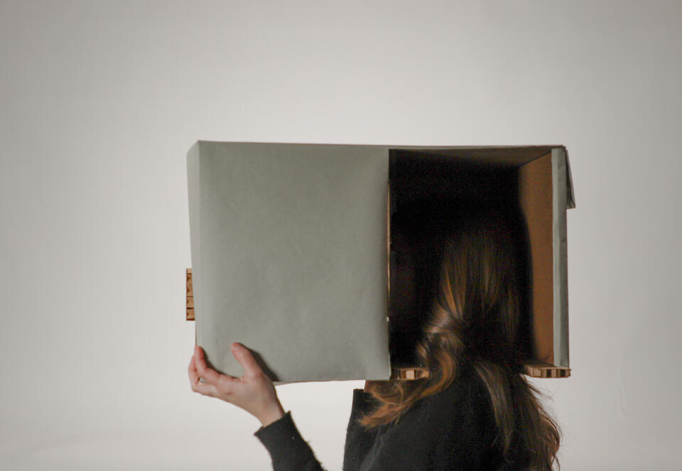 Woman holding cardboard video-projection box over her head