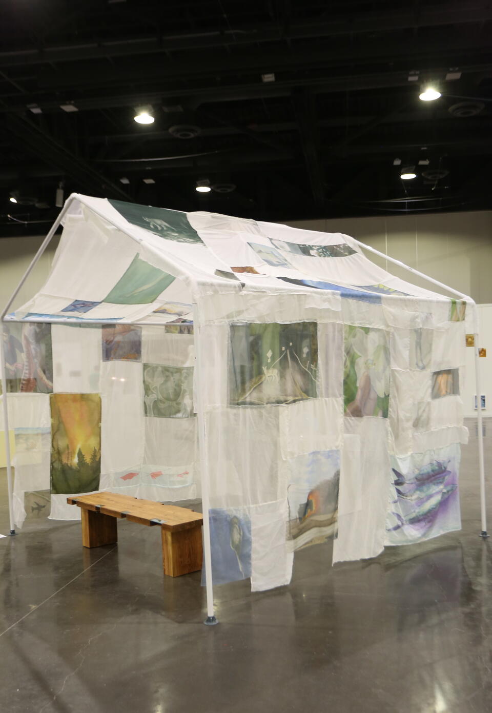 Paintings on transparent fabric draped over house frame 