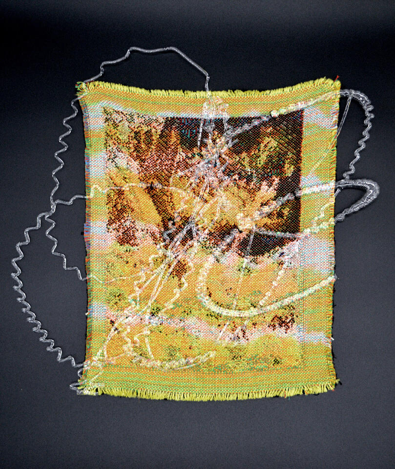 A small-scale yellow abstract weaving placed on a black background with a thin and swirly glass layer on top.
