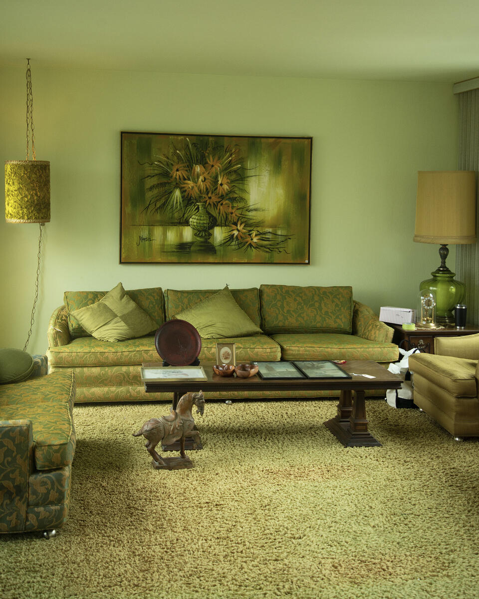 An monochromatic (olive green) interior space of a mid-century modern living room paired with matching furniture. On the floor is a sculpture of a horse figurine and a coffee table. 