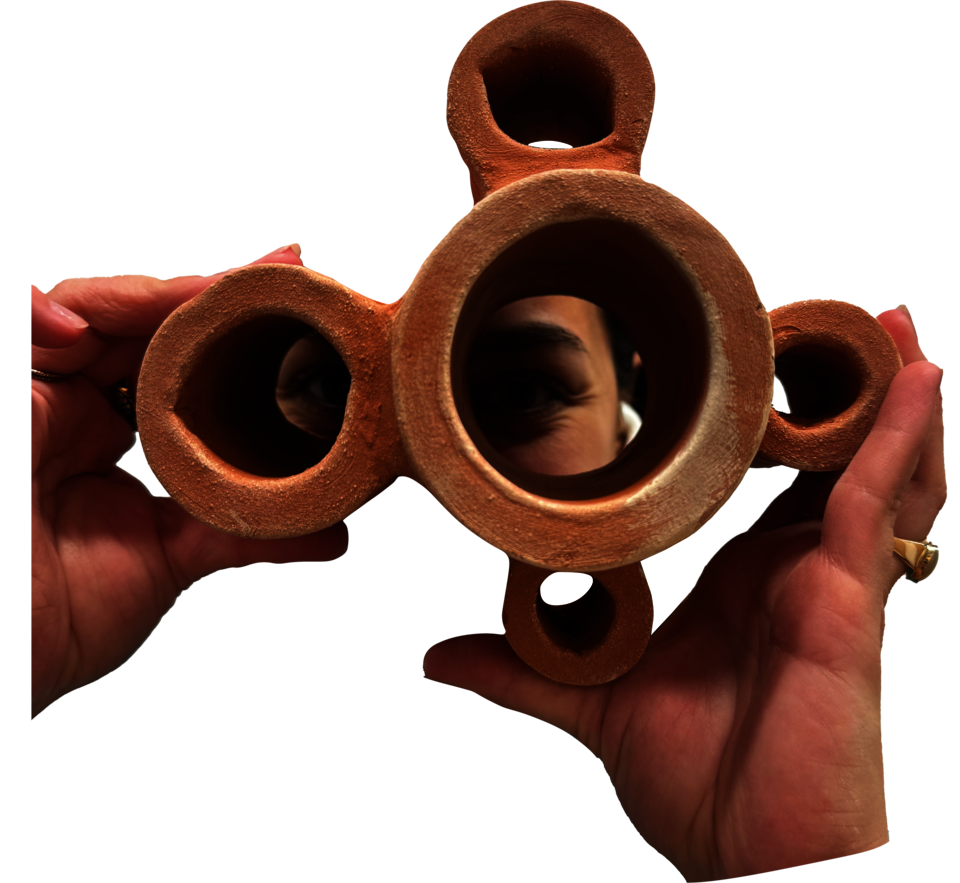 Fired terracotta module used as binaculars. It consists of cylinders that connect at each others tangencies. Total of 5 cylinders, one at the center, largest, and 4 surrounding it; they get smaller in clockwise direction.