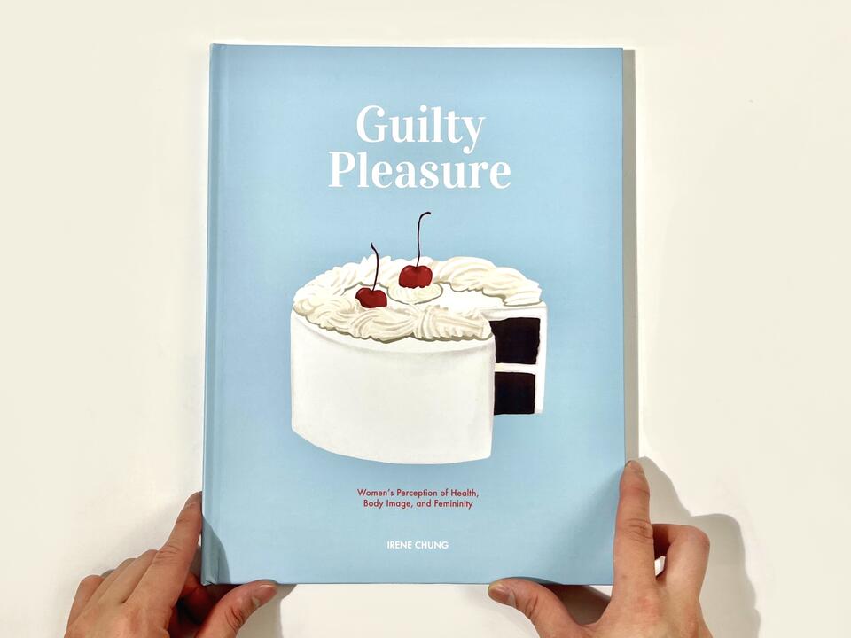 A photograph of the book cover, which features a creamy white cake with cherries on top, sitting on a baby-blue background