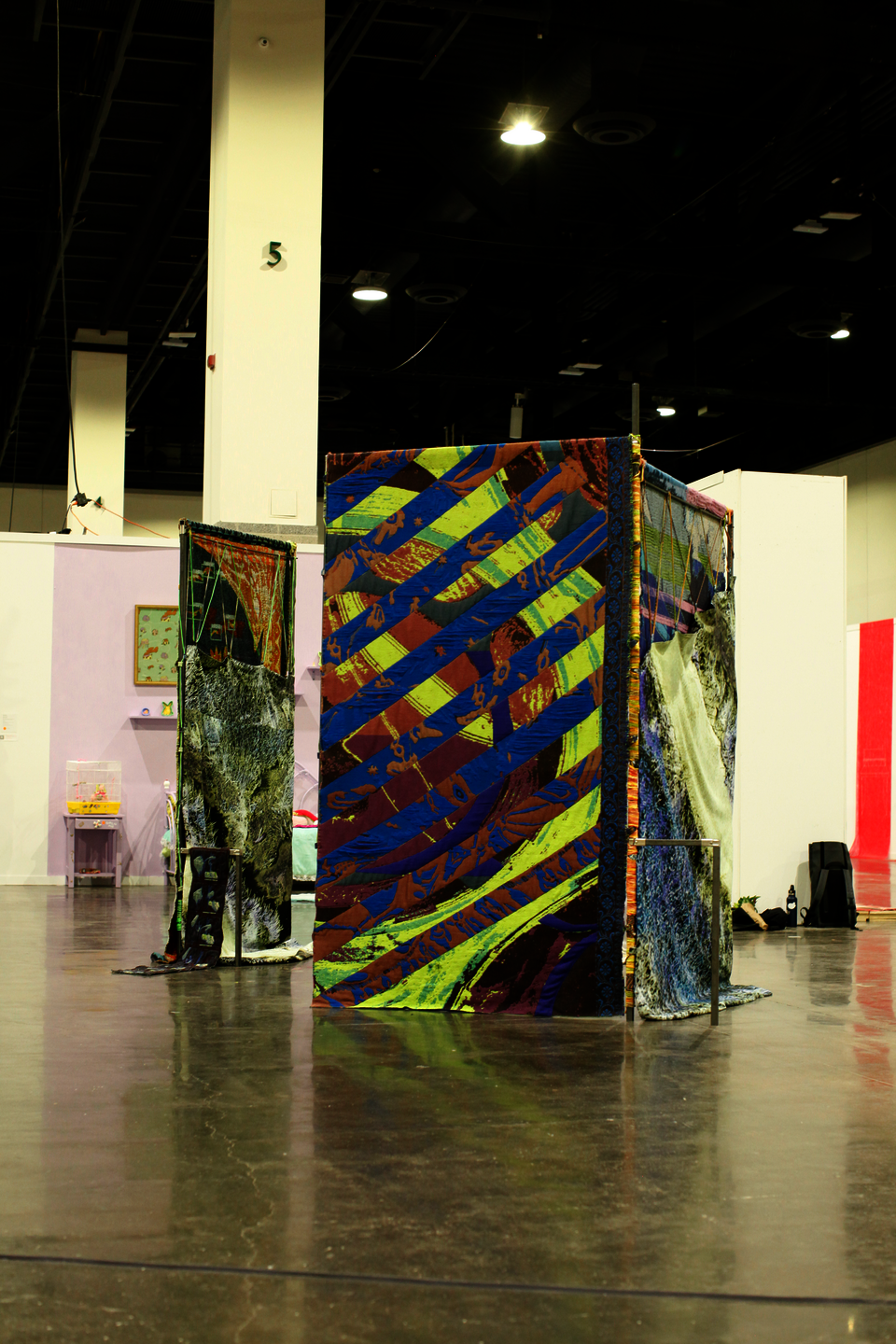 Large scale installation of metal steel frames with colorfull weavings standing in the middle of the floor at the convention center.