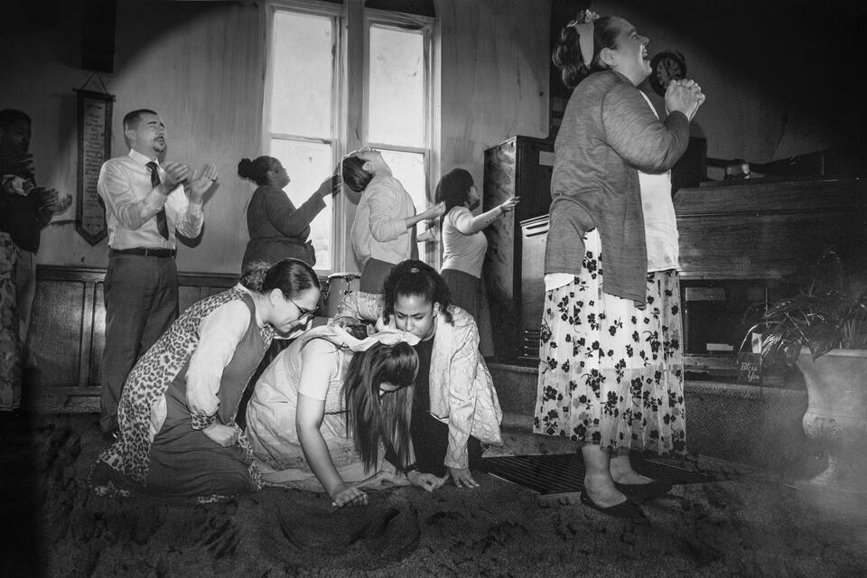 A ribbon in her hair, she falls weeping, held by sun; a procession of worshippers turn faces to God, a click, a pop of light.